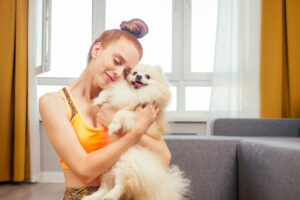 redhaired woman hugging a fluffy white dog