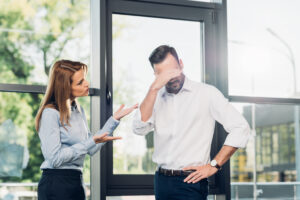 frustrated male colleague speaking with woman at work