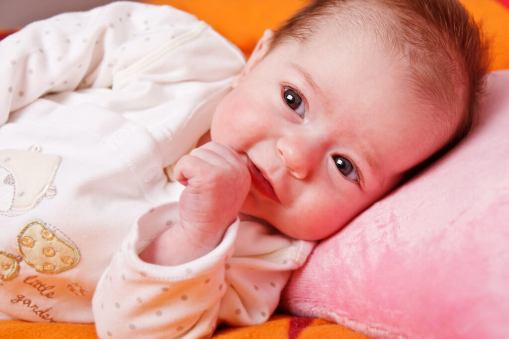 Adorable baby girl lying on a soft blanket and watching