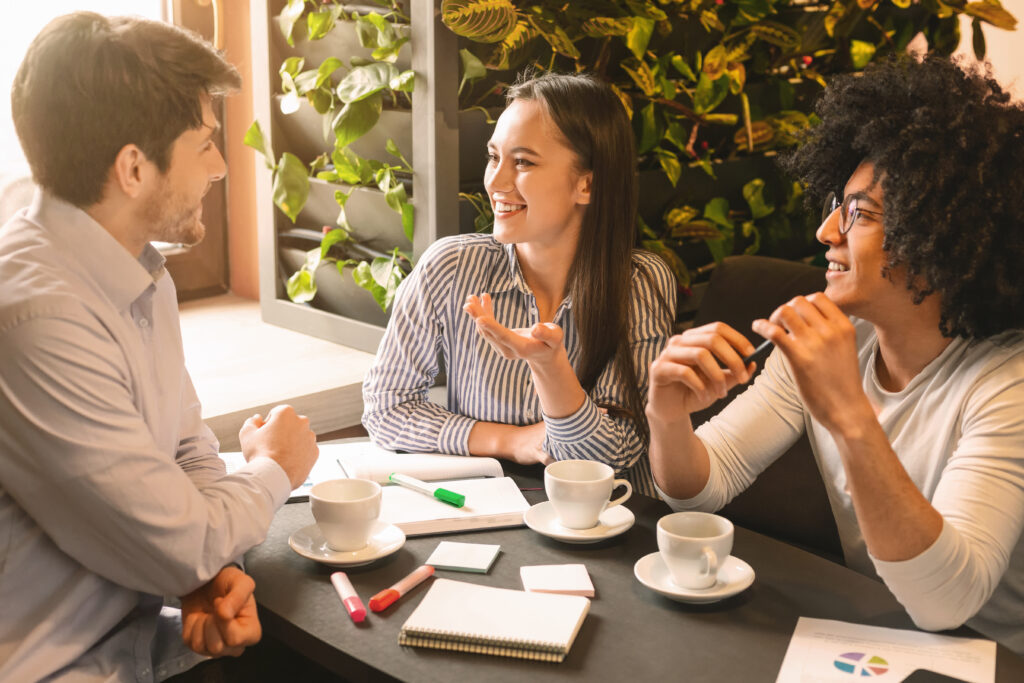 Young colleagues discussing project and marketing strategy in cafe