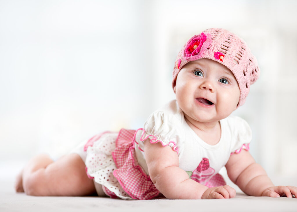 pretty smiling baby girl lying on stomach and looking up