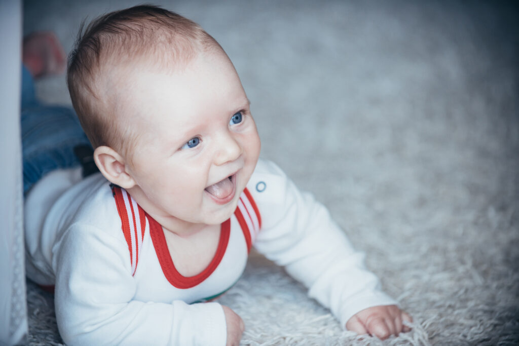 Newborn baby with blue eyes smile on floor at home