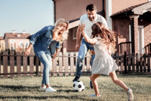 Family playing soccer together in yard