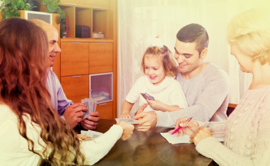 Baby Boomer grandparents playing card game with grandchildren